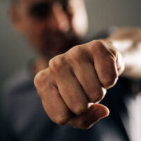 closeup of a young caucasian man throwing a punch to the observer, with a dramatic effect